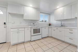Kitchen featuring white appliances, white cabinets, light countertops, light tile patterned floors, and recessed lighting