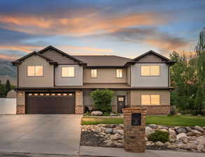 Craftsman house with driveway, an attached garage, board and batten siding, and brick siding
