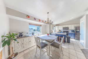 Dining area with light tile patterned floors, a chandelier, and lofted ceiling