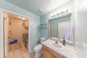 Bathroom with vanity, light tile patterned floors, washer / dryer, and a textured ceiling