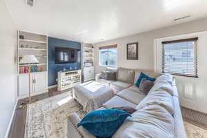 Living room with wood finished floors and built in features