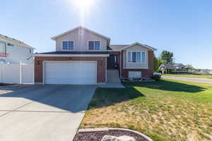 View of front of house with a garage, concrete driveway, brick siding, and a front yard