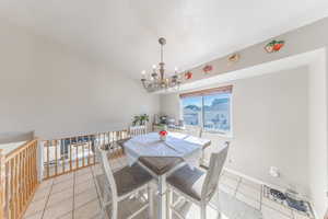 Dining room featuring light tile patterned floors, a chandelier, and lofted ceiling