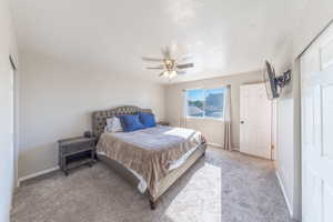 Carpeted bedroom featuring a ceiling fan, a textured ceiling, and a closet
