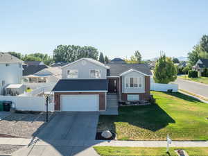 View of front facade with a garage, brick siding, a residential view, and driveway