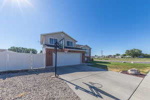 View of front facade with driveway, an attached garage, brick siding, and a gate