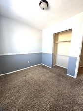 Unfurnished bedroom featuring dark colored carpet and a closet