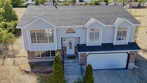 Split foyer home featuring brick siding, concrete driveway, an attached garage, and roof with shingles