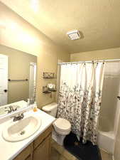 Bathroom featuring vanity, shower / bath combo, and a textured ceiling