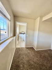 Empty room with light carpet and washer and clothes dryer