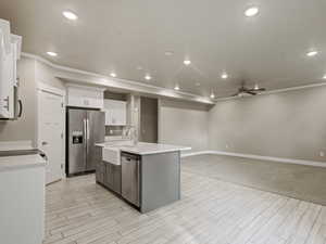 Kitchen featuring white cabinets, appliances with stainless steel finishes, a ceiling fan, recessed lighting, and a center island with sink