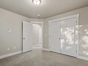 Unfurnished bedroom with carpet flooring, a textured ceiling, and a closet