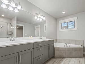 Bathroom featuring double vanity, a shower stall, a garden tub, and recessed lighting