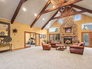 Carpeted living room featuring french doors, high vaulted ceiling, a stone fireplace, and beamed ceiling