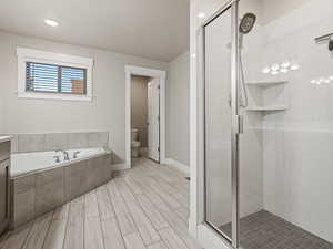 Full bath featuring a shower stall, a garden tub, vanity, wood finish floors, and recessed lighting