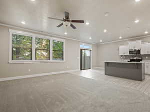 Unfurnished living room featuring crown molding, recessed lighting, a textured ceiling, ceiling fan, and light colored carpet