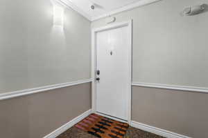 Doorway featuring baseboards and crown molding
