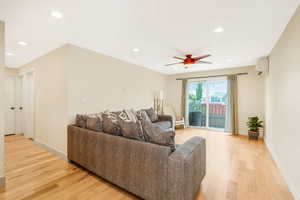 Living room with light wood finished floors, recessed lighting, a ceiling fan, and an AC wall unit