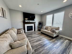 Living room with a tile fireplace, wood finished floors, and recessed lighting