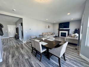 Dining space featuring a tile fireplace, wood finished floors, arched walkways, recessed lighting, and a textured ceiling