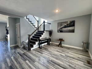 Stairs featuring wood finished floors and a textured ceiling