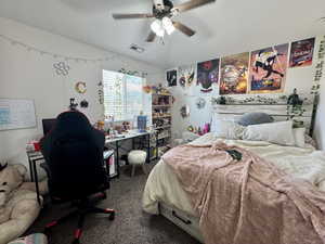 Bedroom with an office area, dark colored carpet, and a ceiling fan