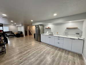 Kitchen with open shelves, modern cabinets, a textured ceiling, open floor plan, and light wood-style flooring