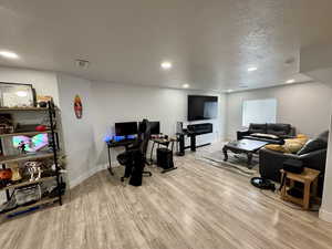 Living room featuring a textured ceiling, light wood-style floors, and recessed lighting