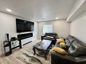 Living area with a textured ceiling, light wood-style floors, and recessed lighting