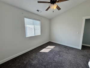 Empty room featuring dark carpet and a ceiling fan