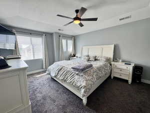 Primary Bedroom with a textured ceiling, dark colored carpet, and ceiling fan
