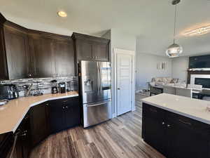 Kitchen with stainless steel fridge, pendant lighting, a textured ceiling, open floor plan, and dark wood finished floors