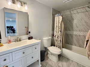 Full bathroom with shower / bathtub combination with curtain, vanity, light marble finish flooring, and a textured ceiling
