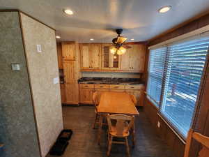 Kitchen with a textured ceiling, dark wood finished floors, glass insert cabinets, ceiling fan, and recessed lighting