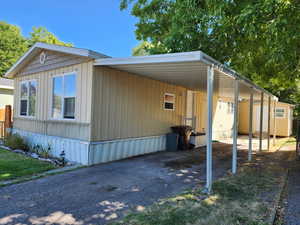 View of home's exterior with asphalt driveway, an attached carport, and an outdoor structure