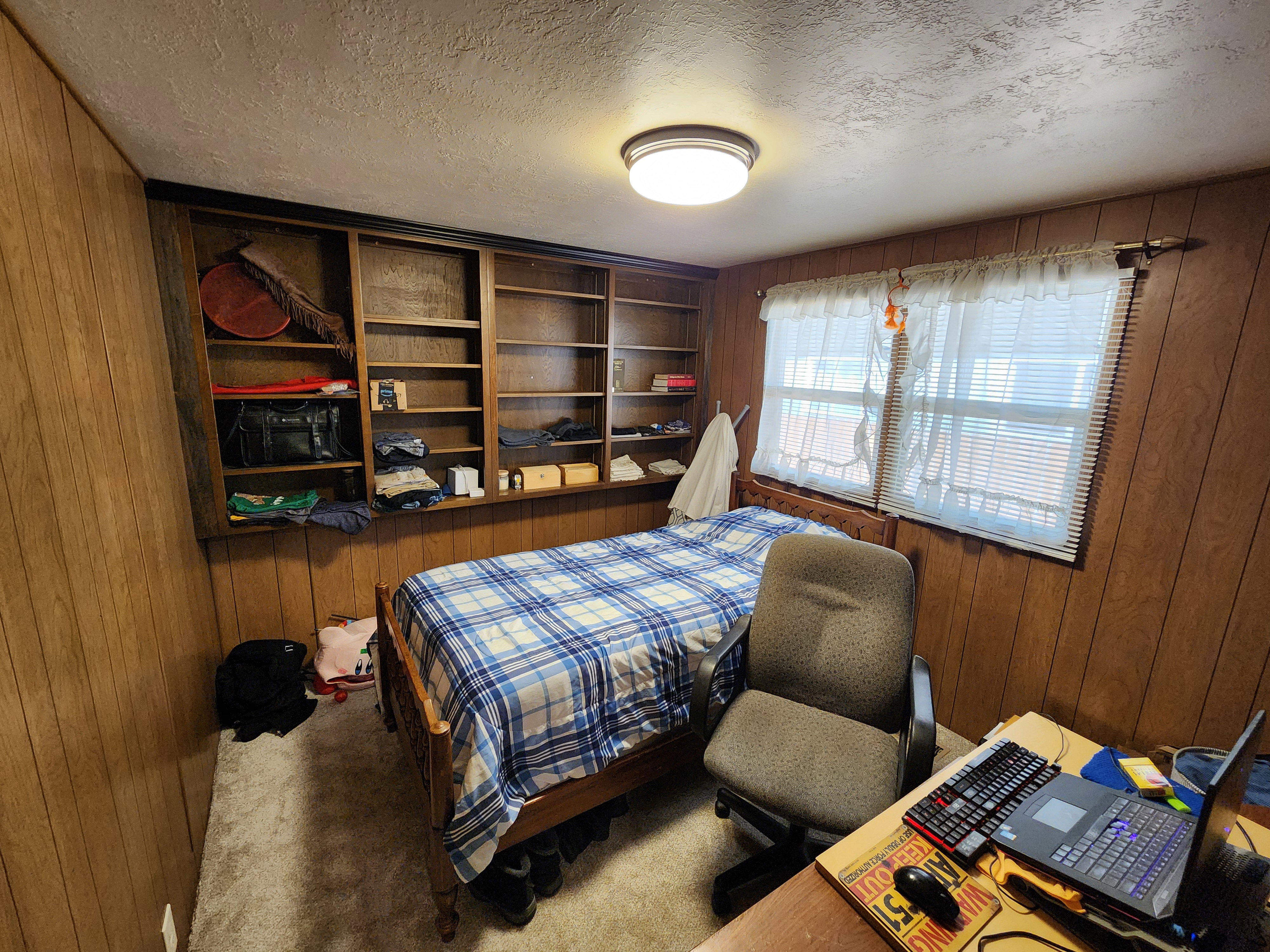Carpeted bedroom with wood walls and a textured ceiling