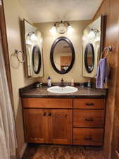 Full bathroom with a textured ceiling and vanity