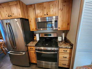 Kitchen featuring stainless steel appliances and dark stone countertops