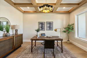 Home office featuring a chandelier, light wood-type flooring, beam ceiling, coffered ceiling, and ornamental molding