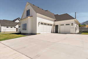 View of property exterior featuring board and batten siding, a garage, brick siding, roof with shingles, and concrete driveway