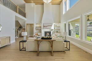 Living room featuring light wood-type flooring, a high ceiling, a fireplace, and stairway