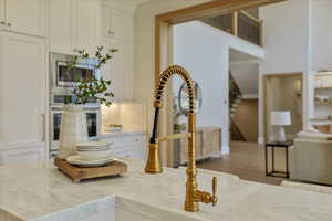 Kitchen view of oven, light stone counters, and stainless steel microwave