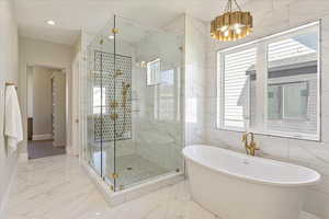 Full bathroom featuring marble tiled floors, a soaking tub, a marble finish shower, recessed lighting, and a chandelier
