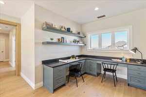 Office featuring built in desk, light wood-type flooring, and recessed lighting