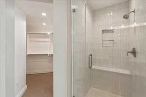 Full bath with a shower stall, recessed lighting, and a spacious closet