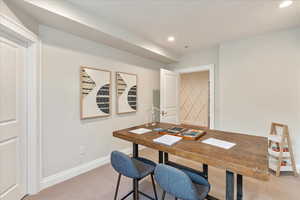 Home office with light colored carpet and recessed lighting