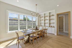 Dining area featuring light wood-style floors, a chandelier, recessed lighting, and built in shelves