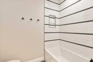 Full bath featuring shower / bath combination and baseboards