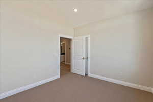 Carpeted empty room featuring high vaulted ceiling and recessed lighting