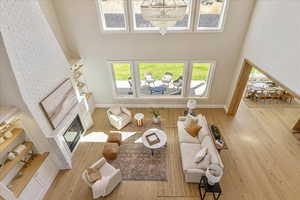 Living area with a towering ceiling, wood finished floors, a glass covered fireplace, and a chandelier